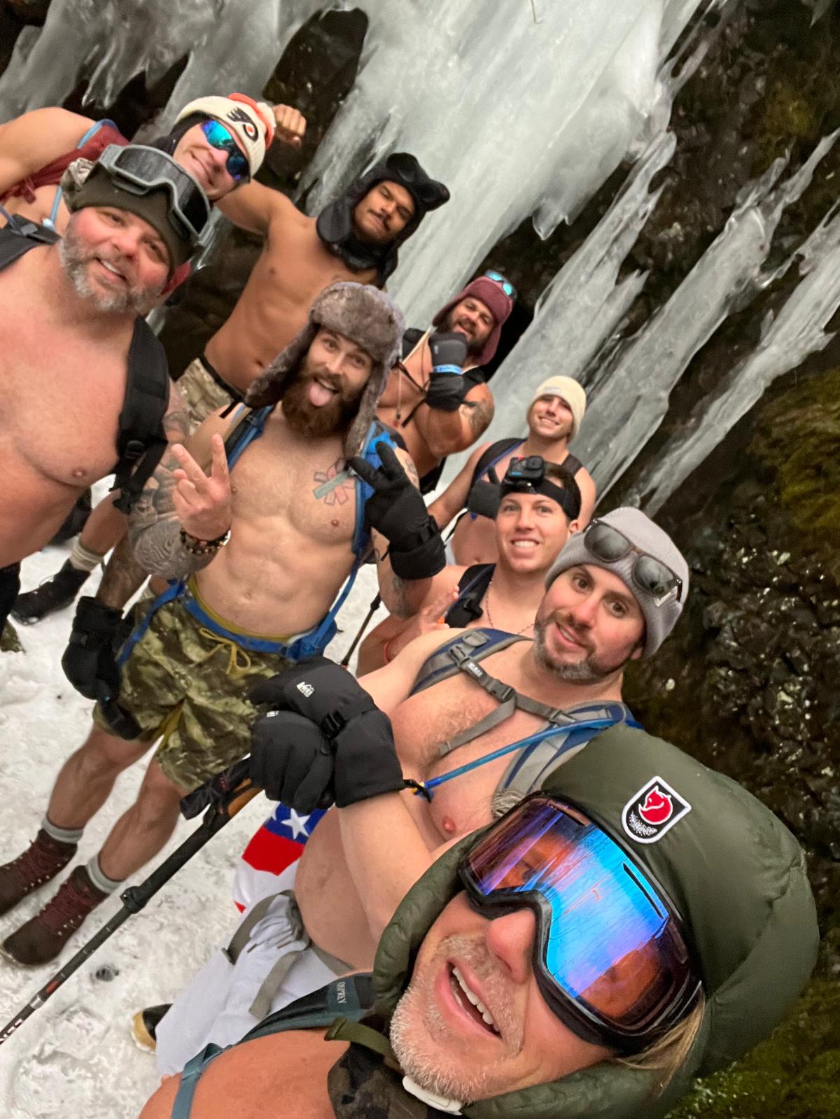 A group of adventurers in winter gear beside a frozen waterfall