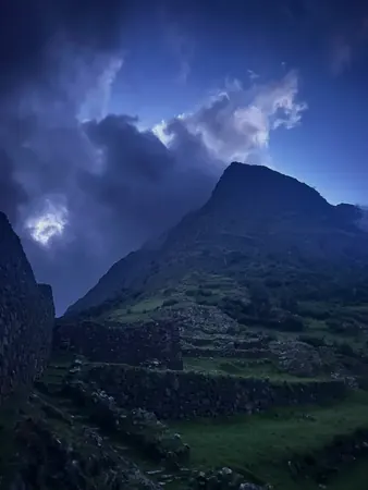 A dark mountain ridge at dusk with storm light behind the peak on a retreat location